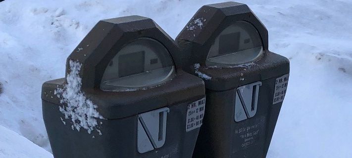 A parking meter in a snowbank.