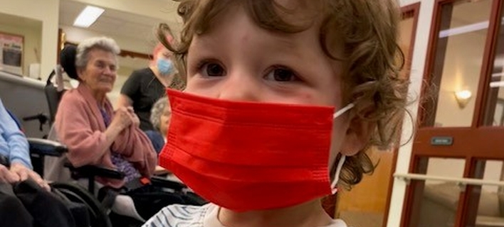 Child wearing mask with a senior in the background