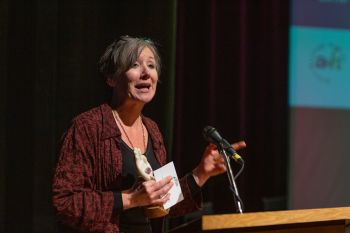 woman accepting an award on stage at podium