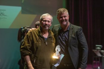 man presenting another man with award on stage