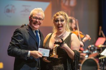 man presenting an award to performer on stage