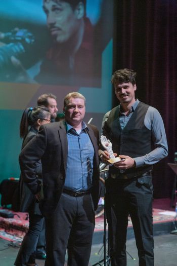man presenting another man with award on stage