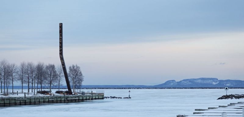 a tall sculpture by the water