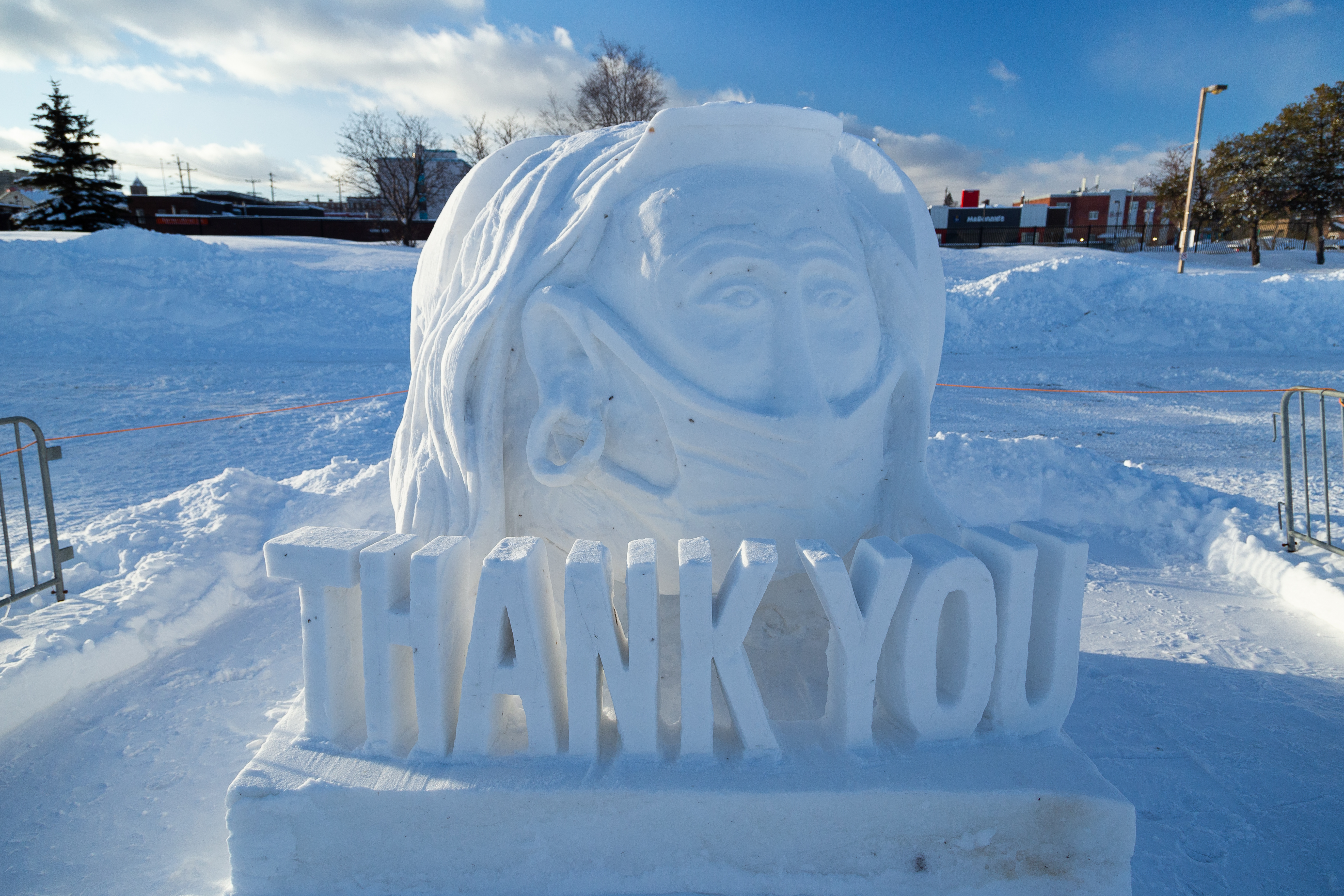 A snow sculpture of the words thank you and a masked nurse portrait