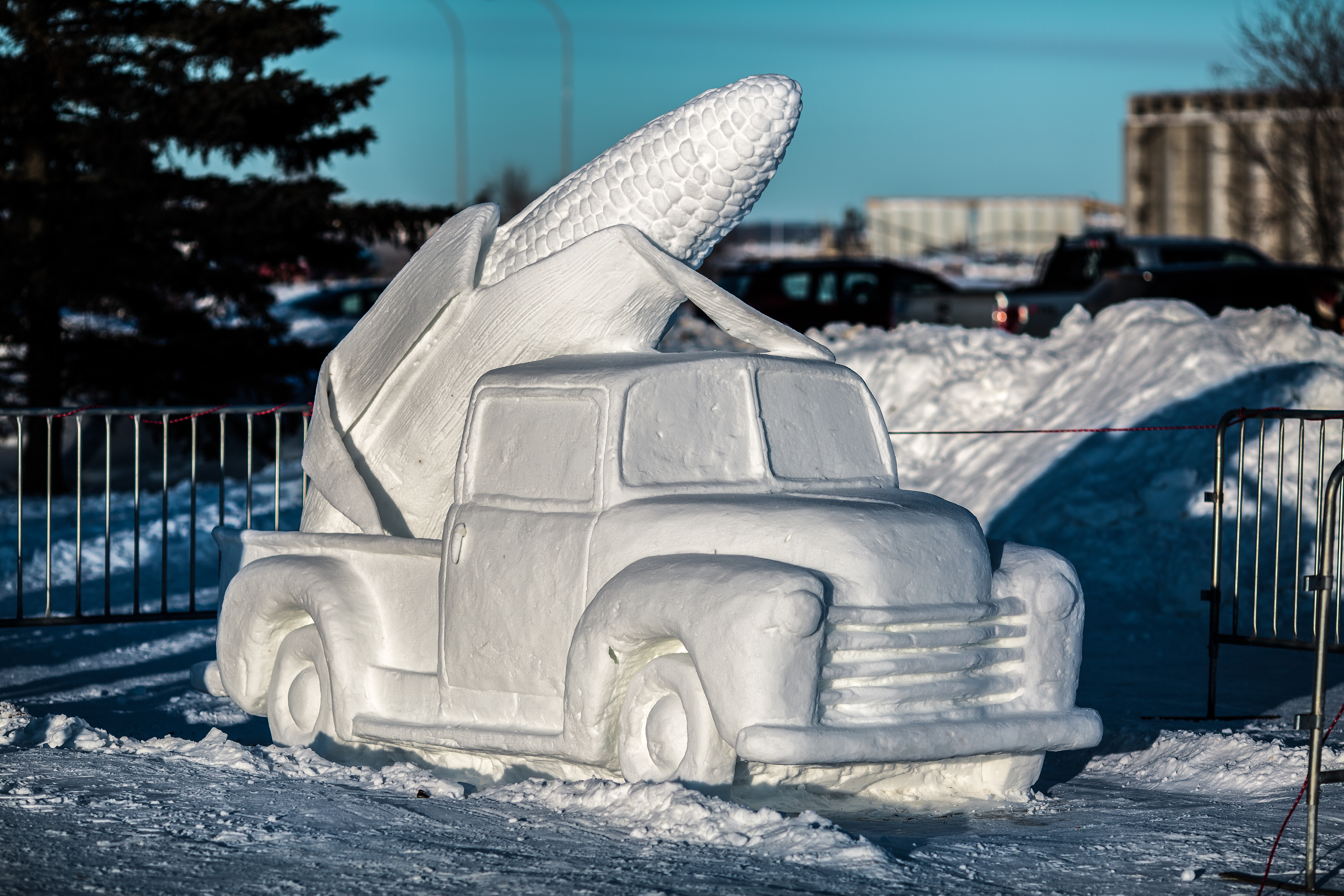 A snow sculpture of a pickup truck with a large cob or corn