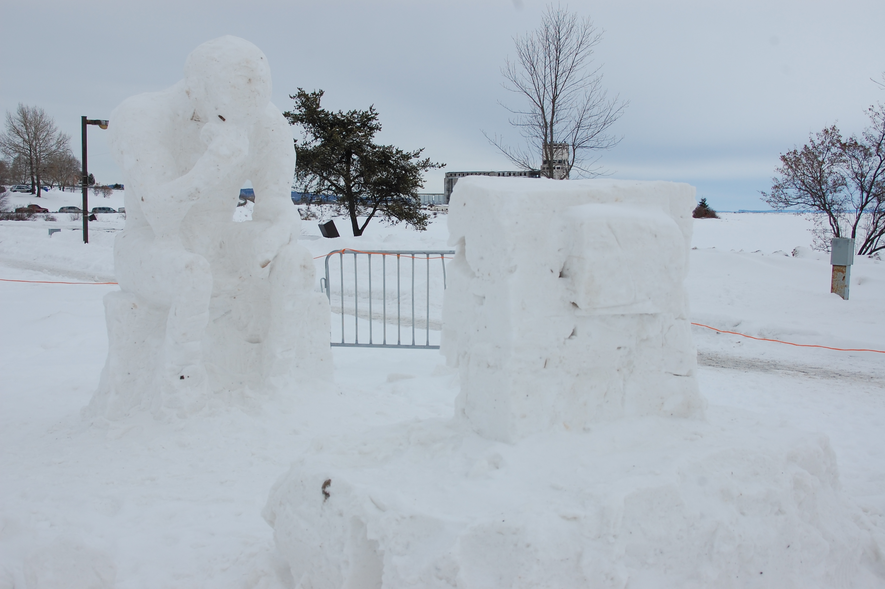 A snow sculpture of a seated figure staring at an object