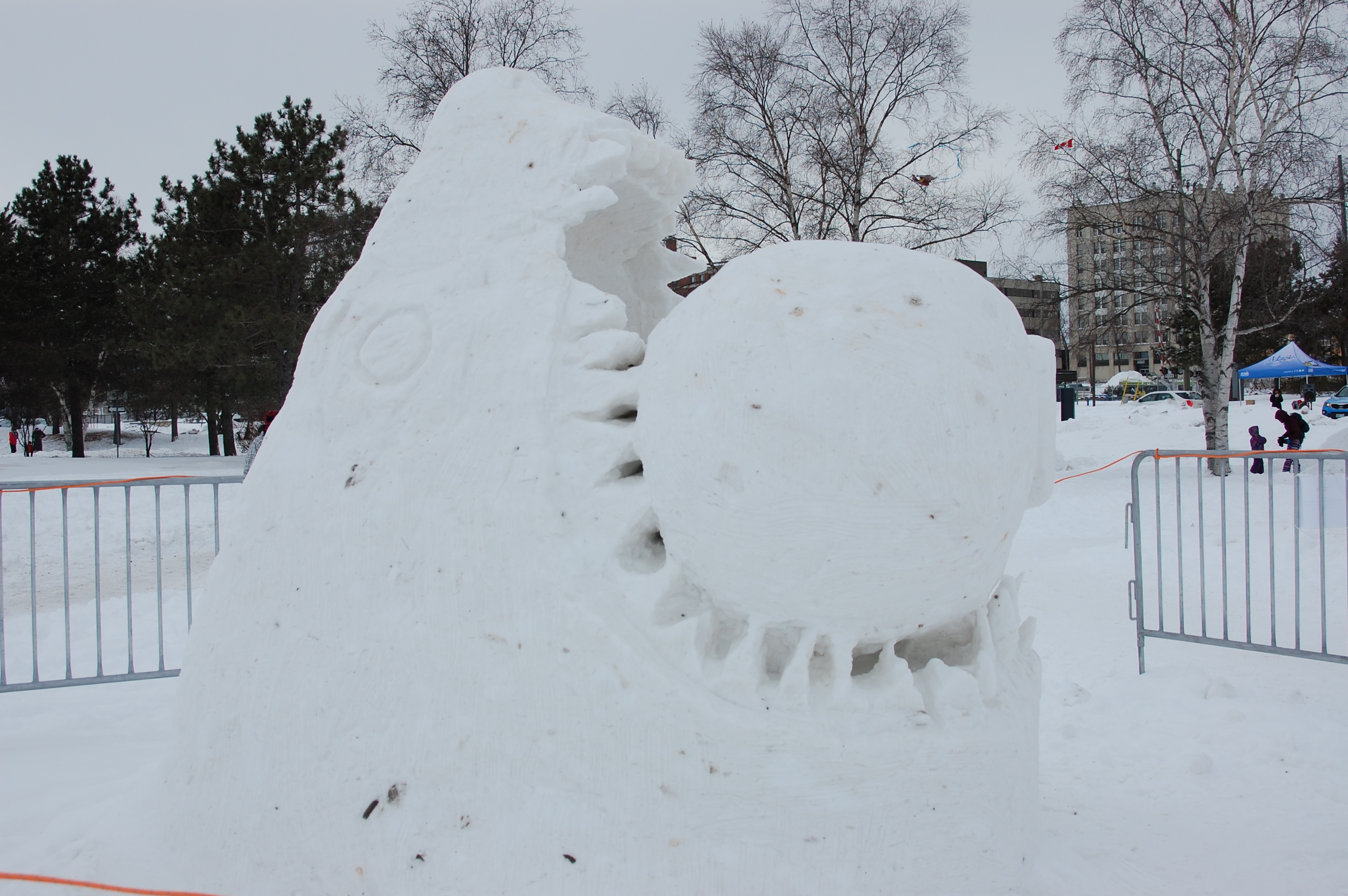 A snow sculpture of a shark head biting on a giant snowball