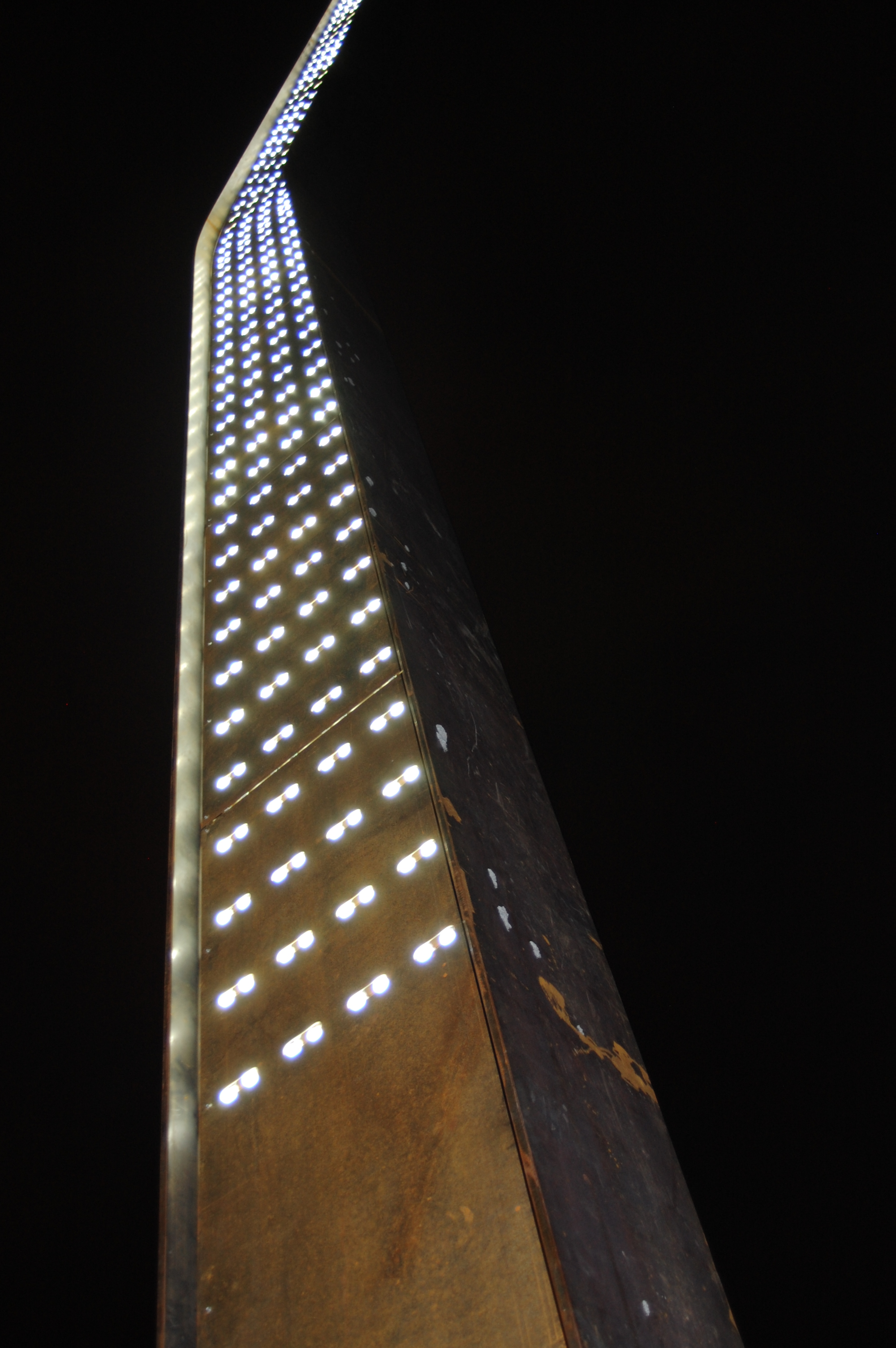 A photo of the Jiigew sculpture at night time with the lights shining