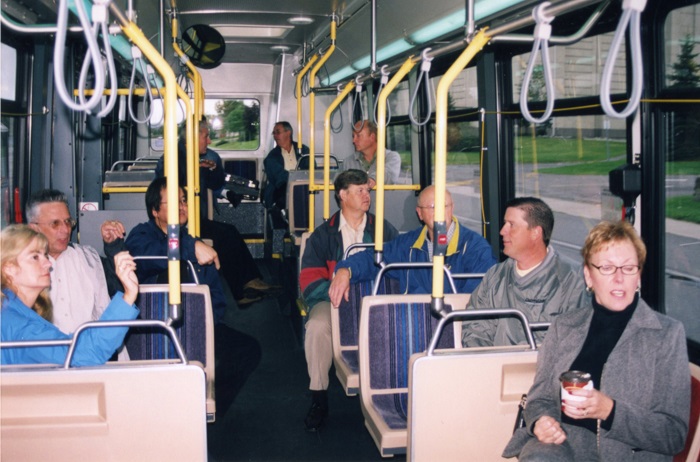 Several people sitting on a bus going down the street