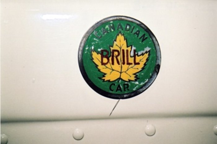 A green circle with a gold maple leaf in the centre overlaid with the word Canadian Car, Brill