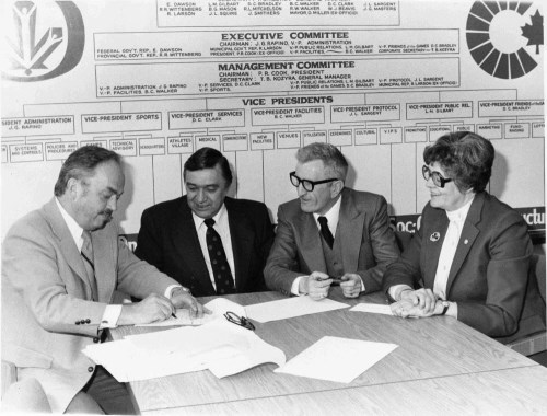 Four people sitting at a table preparing to sign a document