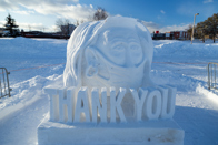 A snow sculpture of the words thank you and a masked nurse portrait