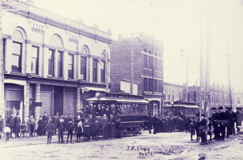 Crowds of people surrounding rail cars on the street