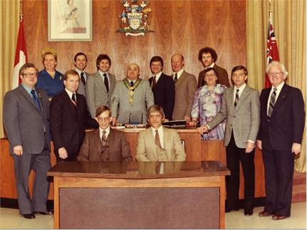 The 1981 City Council of Thunder Bay stand and sit together in an official portrait with the mayor in the centre