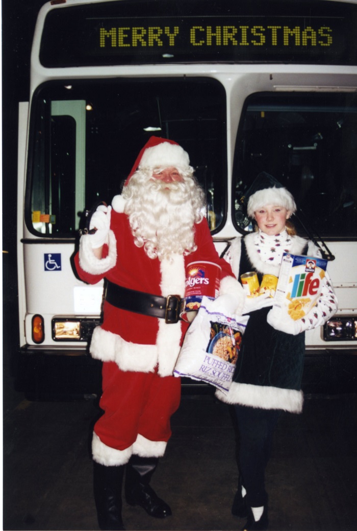 Santa in front of a bus with his helper