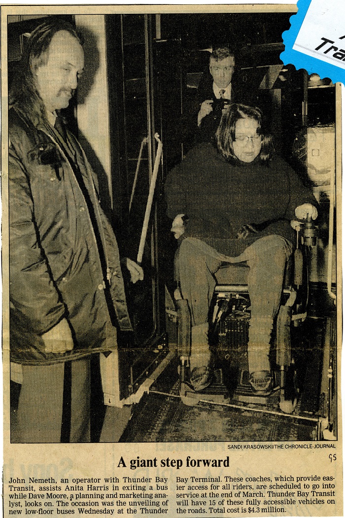 A newspaper article showing a man helping another person on a bus in a wheelchair