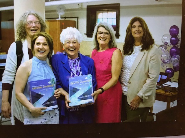 Lynda McKeown with copy Dental Hygiene textbook and unidentified individuals