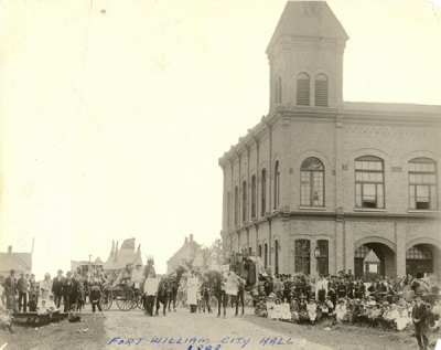 A black and white photo of the first City Hall with people standing out front