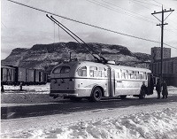 An electric trolley running along a street with railway cars in the background