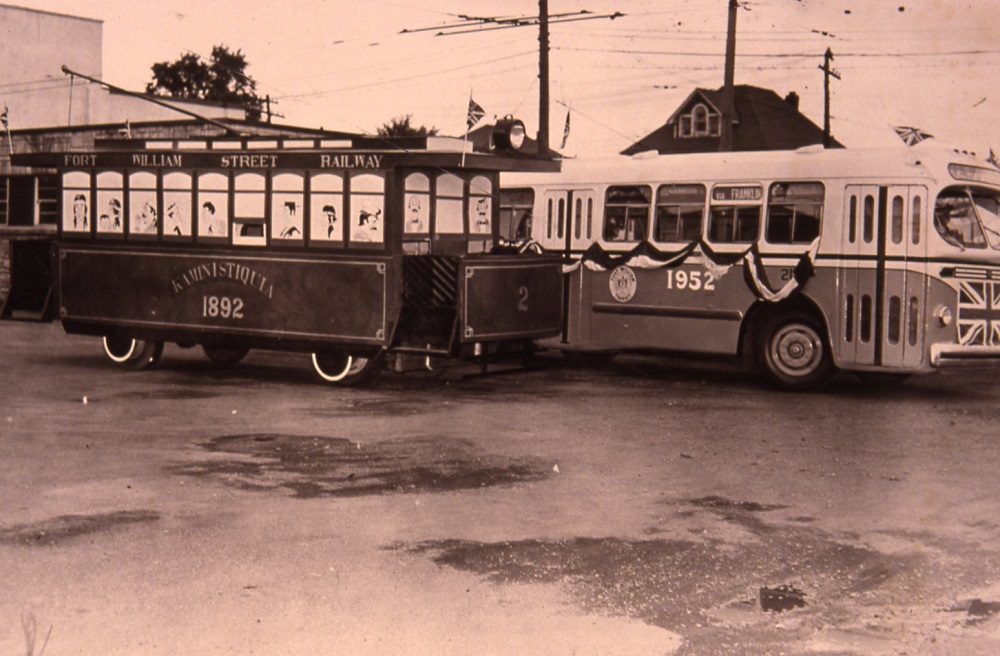 a decorated street car with a gas bus beside it, also decorated.