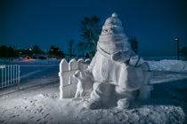 A snow sculpture of a young girl delivering Chronicle Journal newspapers with her dog