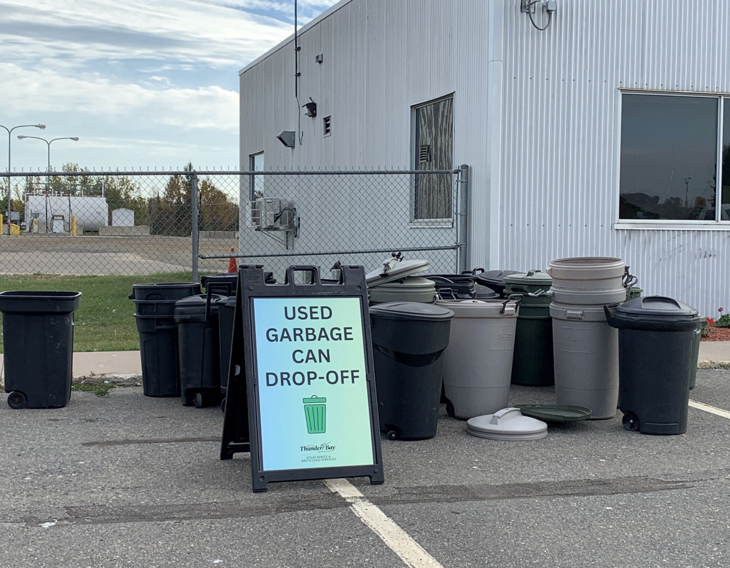 used garbage cans, and sign with text: USED GARBAGE CAN DROP-OFF