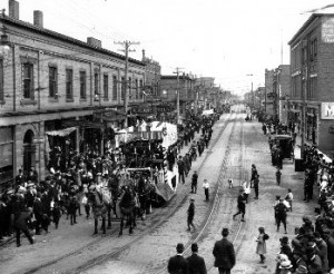 a group of workers walking along a street with a streetcar in the middle celebrating labour day