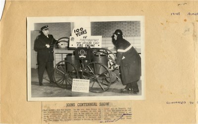 a man standing beside a cart with wheels and a tank