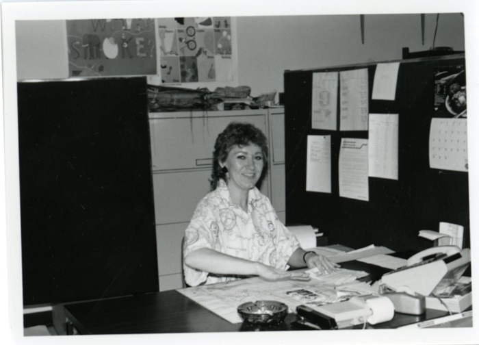 A woman sitting at a desk and smiling towards the camera in an office