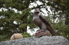 A large stone with a falcon statue with a rock egg beside it