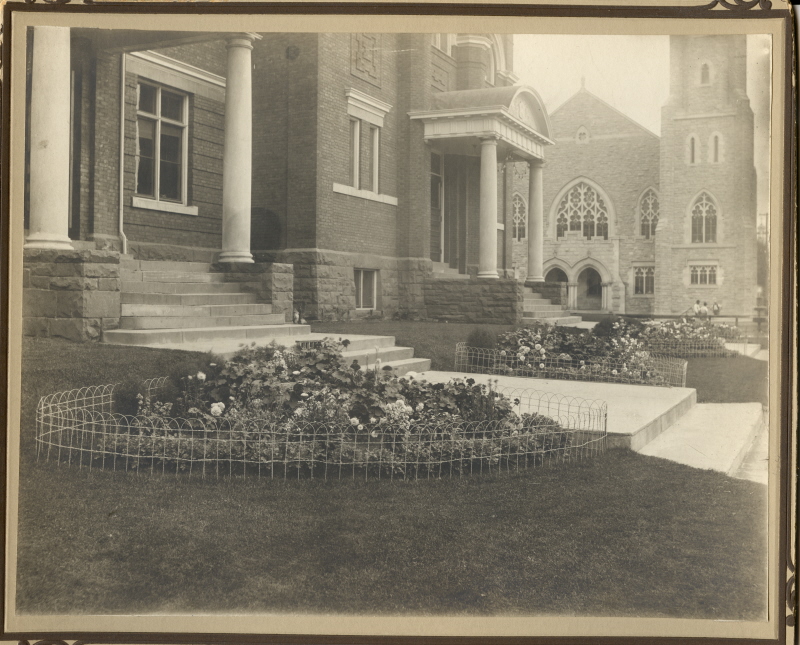 Two flowerbeds filled with flowers in front of a building