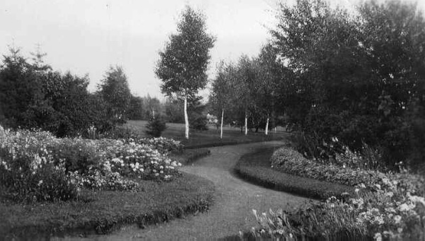 Gardens sitting on either side of a pathway with trees in back