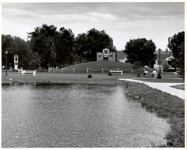 A pond with pathways and a concrete structure behind