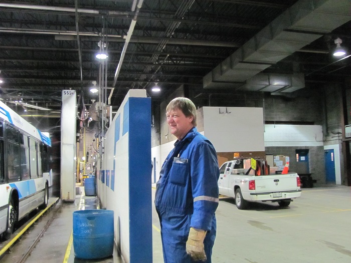 A man turning and smiling at the camera while inspecting buses