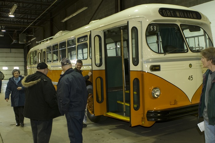 A group of people looking at a restored orange and white bus