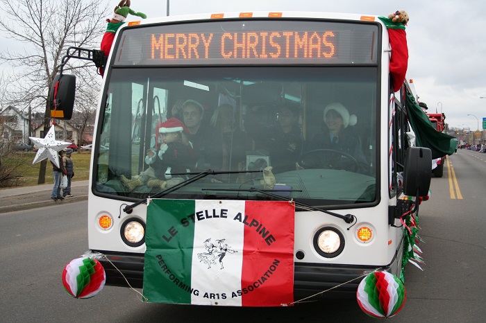 A bus decorated in red, green and white says Merry Christmas on its sign