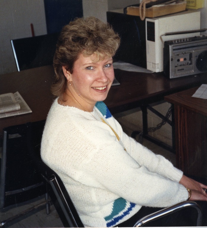 A woman sitting and turning towards the camera smiling