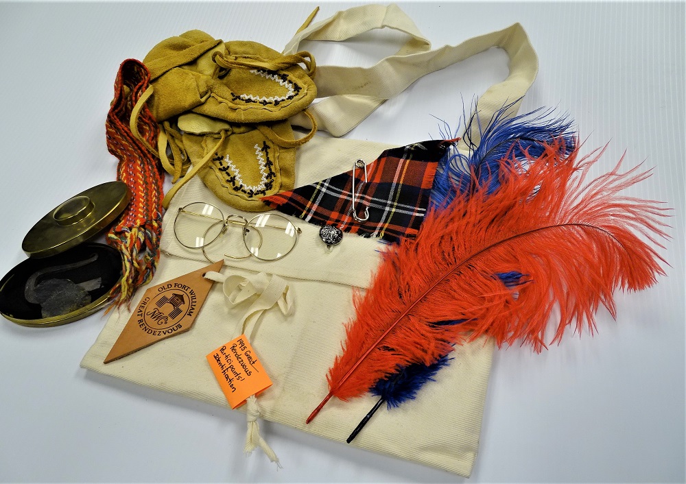 Collection of Old Fort William Great Rendezvous items including glasses, a scarf and moccasins