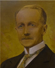 Mayor James Crooks sits wearing a black suit, brown tie and has blonde hair